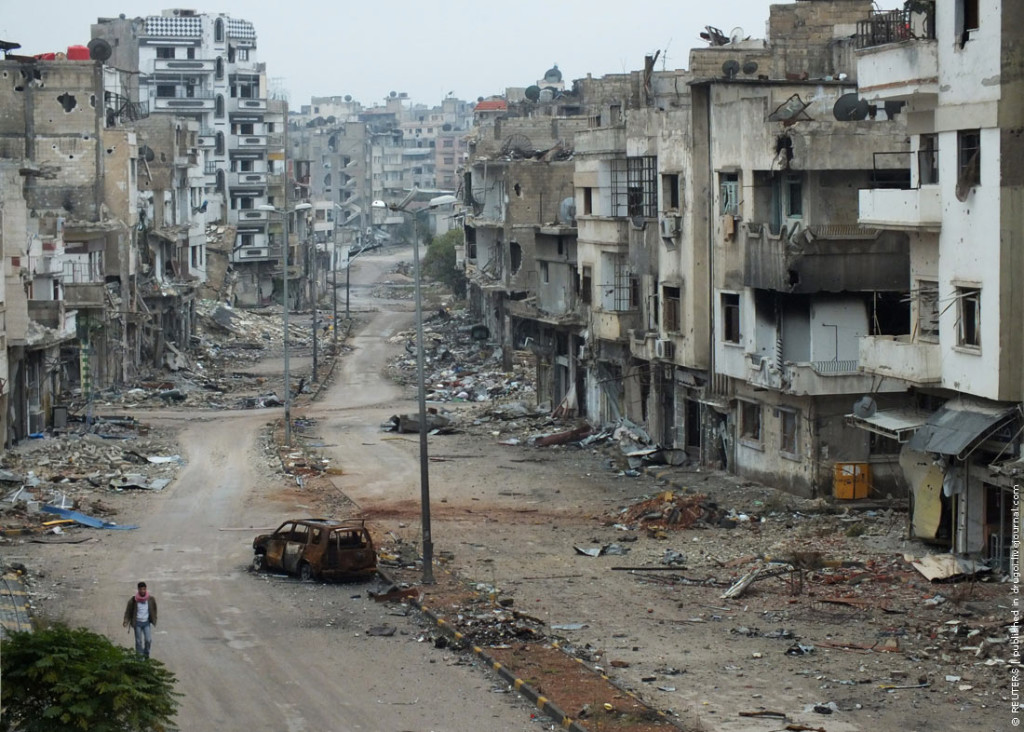 A man walks past a burnt car and damaged buildings along a street at the al-khalidiya neighbourhood of Homs November 19, 2012. REUTERS/Yazan Homsy (SYRIA - Tags: CONFLICT) - RTR3AMBE